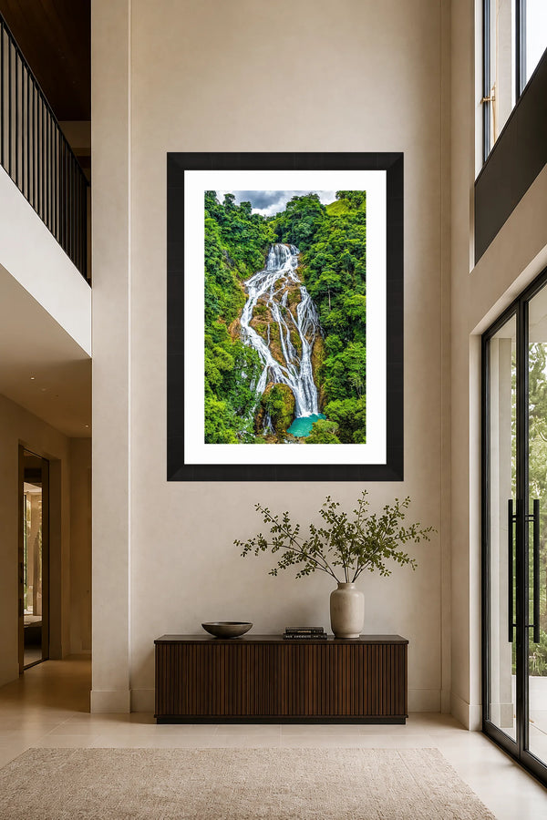 El Rey rainforest waterfall fine art print framed on a tall warm limewash wall in a serene double-height modern entry and staircase gallery