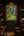 Garden Falls rainforest waterfall fine art print framed and lit on a dark forest-green paneled wall in a moody luxury home study with walnut and leather