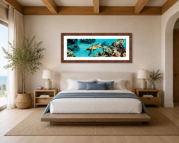 Honu Harmony panoramic Hawaiian green sea turtle and coral reef fine art print framed above the headboard in a serene coastal-modern luxury primary bedroom