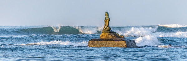A weathered mermaid sculpture against the surf at Esterillos Oeste, Costa Rica