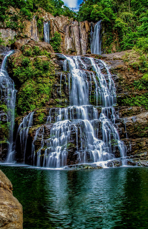 Waterfalls spilling into a tranquil rainforest pool