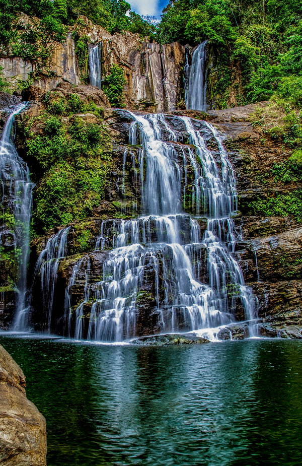 Waterfalls spilling into a tranquil rainforest pool