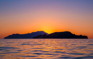 Sunset over the Aegean Sea with silhouetted islands near Milos, Greece