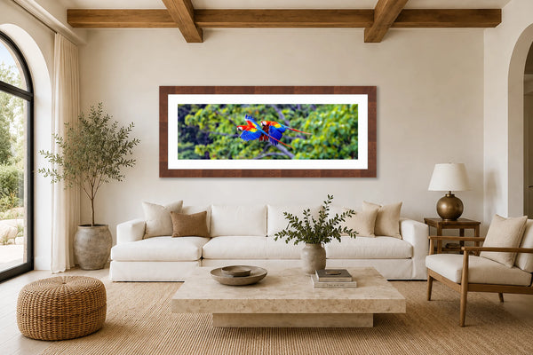 La Pareja panoramic scarlet macaws fine art print framed above a long white sofa in a bright airy contemporary luxury living room