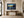 Lost and Found coastal sunset fine art print framed in black above a wood console in a grand luxury foyer with arched windows