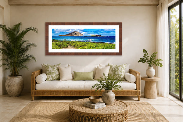 Ocean Breeze panoramic Hawaii coastline fine art print framed in walnut above a rattan daybed in a bright tropical lanai sunroom