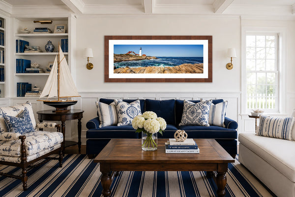 Portland Head Light Maine lighthouse panoramic fine art print framed in walnut above a navy sofa in a traditional New England coastal living room