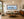 Siren of the Waves panoramic mermaid sculpture seascape fine art print framed in black above a sofa in a warm mid-century modern living room