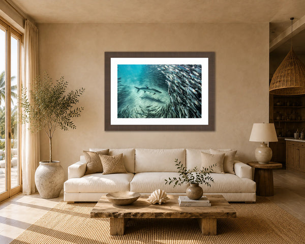 The Mullet Run tarpon and silver baitfish print framed above a sofa in a warm sandy organic-coastal living room